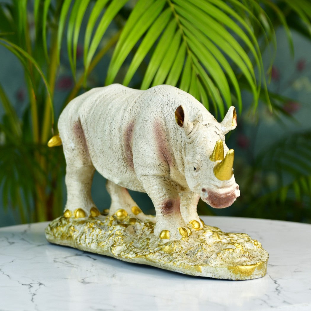 Luxury home decor figurines white rhinoceros with gold accents on marble surface with green plants background