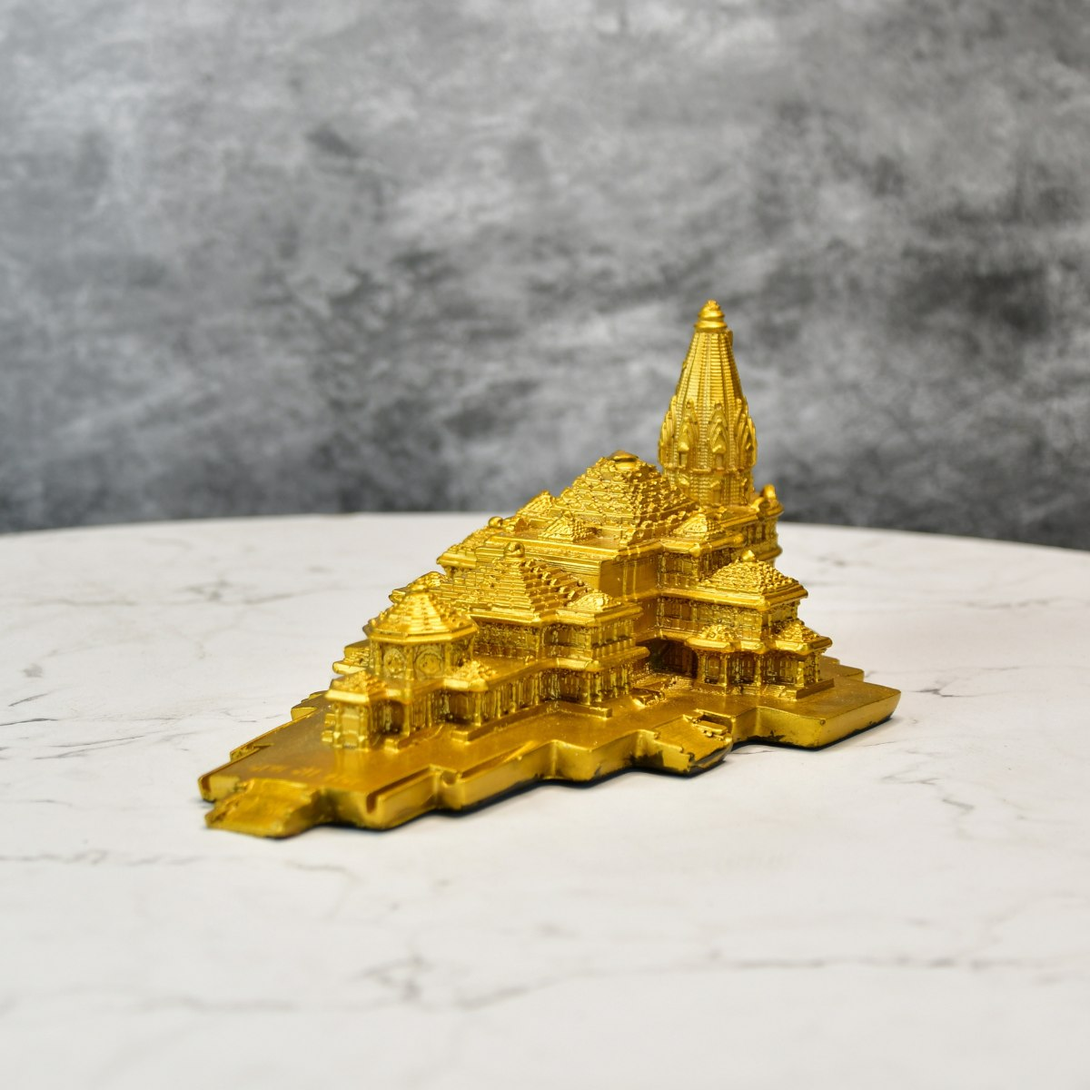 Golden resin decorative god idols for home showcasing intricate temple design on marble surface