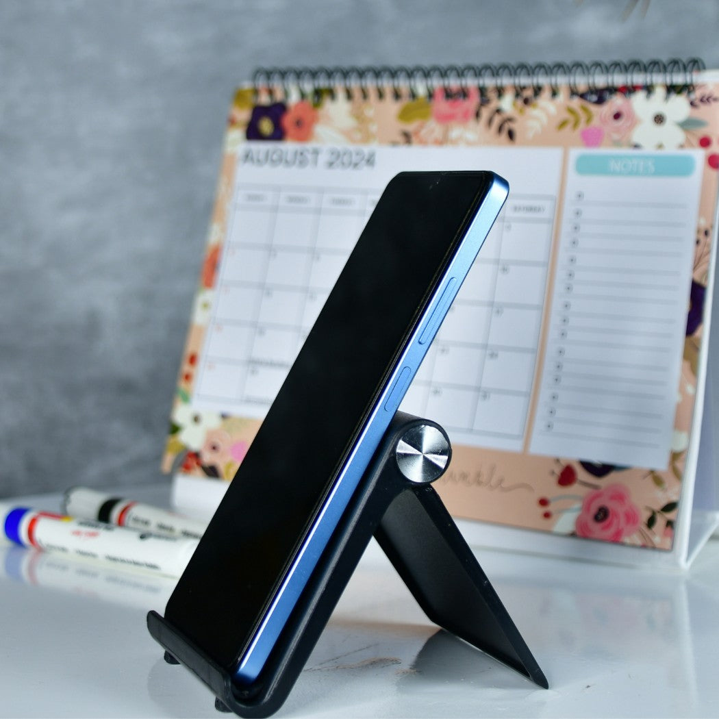 Stylish desk mobile stand holding a smartphone on a white desk with a floral calendar in the background