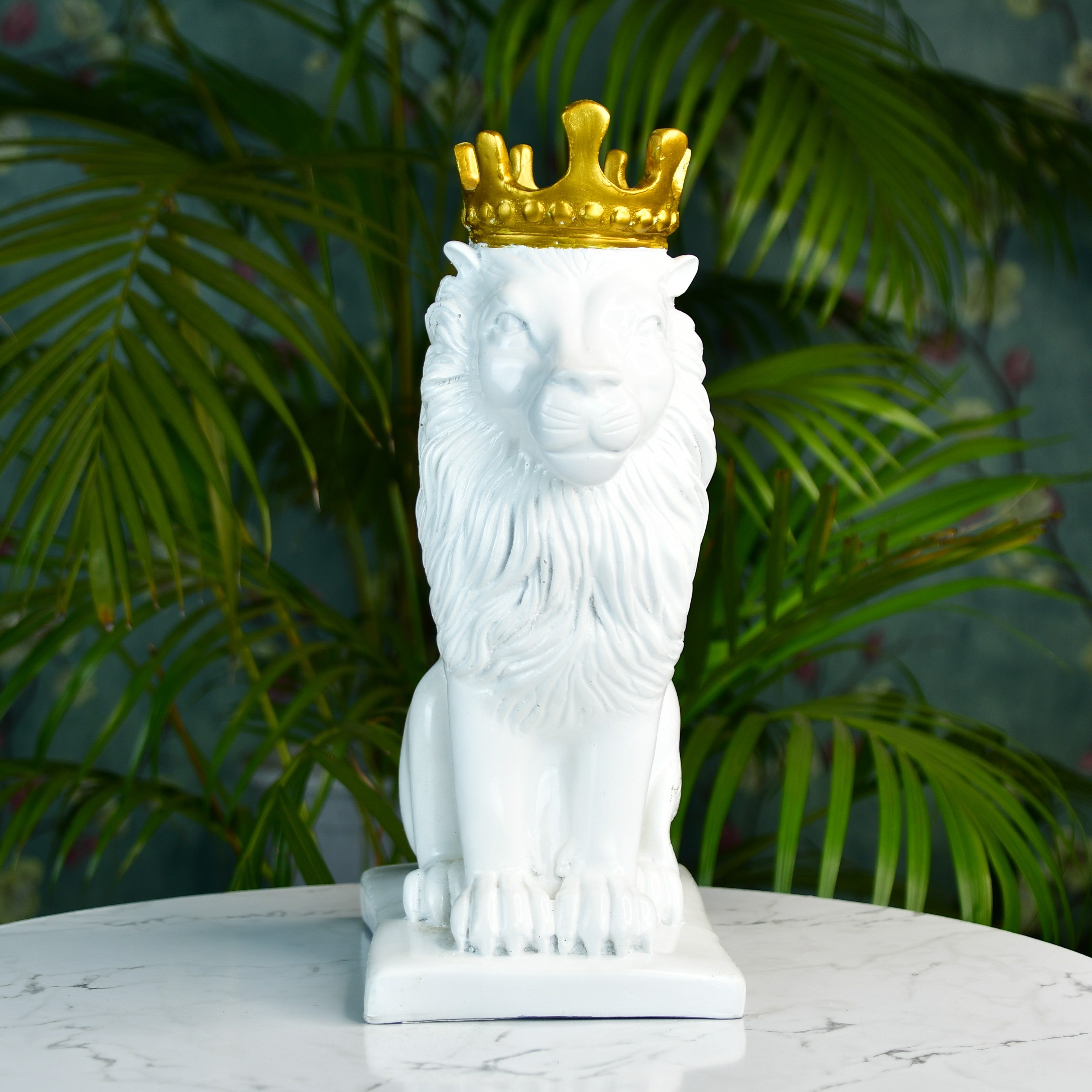 MAYII white lion figurine with a gold crown sitting on a marble tabletop with green plants background